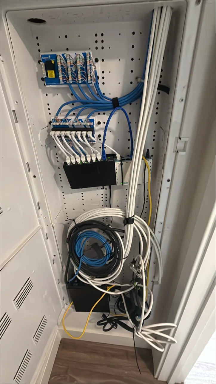 Home network cabinet before Mitec cleanup, with loose cables and equipment hanging through the enclosure