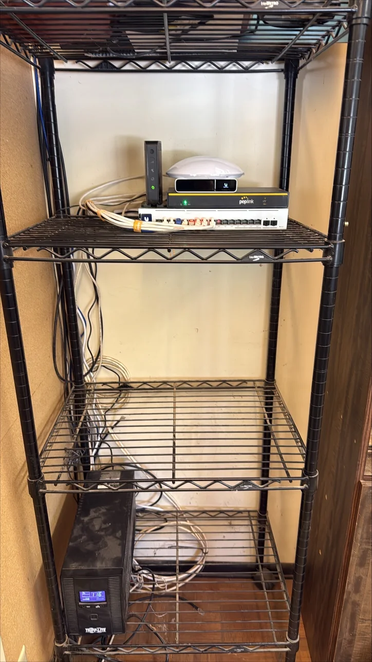 The same business technology shelf after Mitec cleanup, with core equipment arranged together and cabling organized