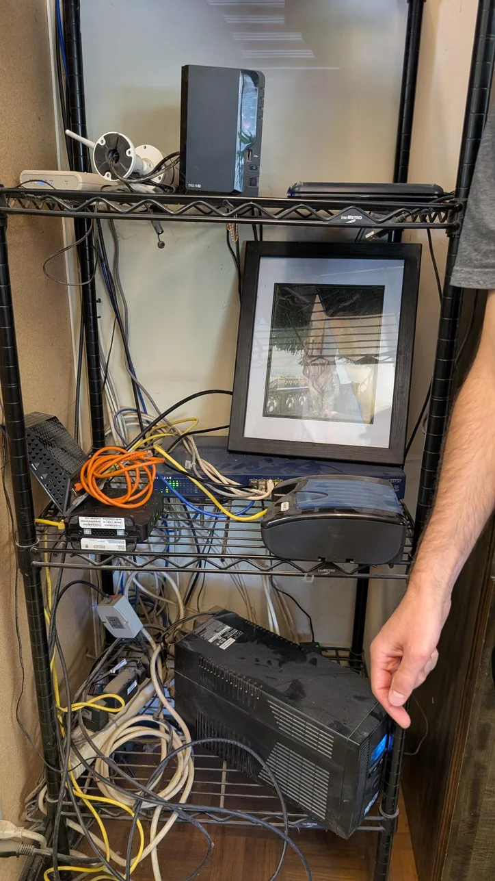 Business technology shelf before Mitec cleanup, with loose equipment and tangled cables