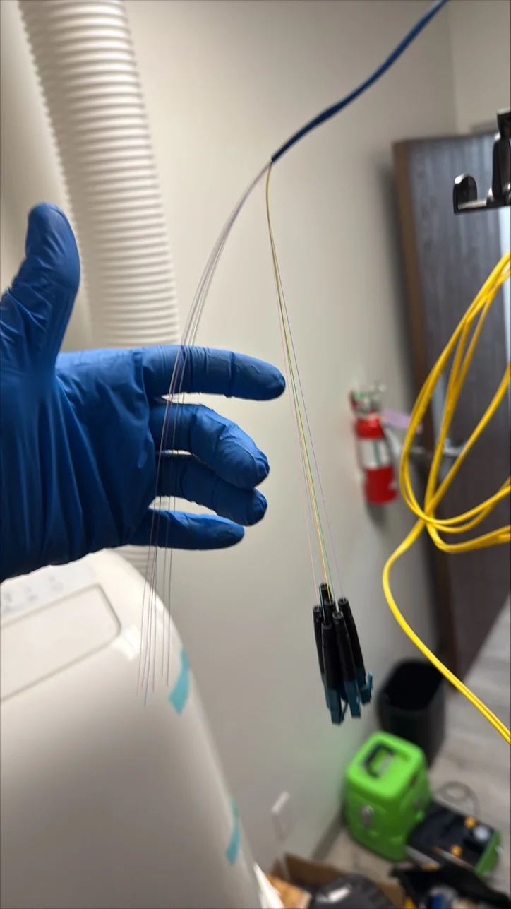 Gloved Mitec technician holding prepared fiber strands during fiber termination work